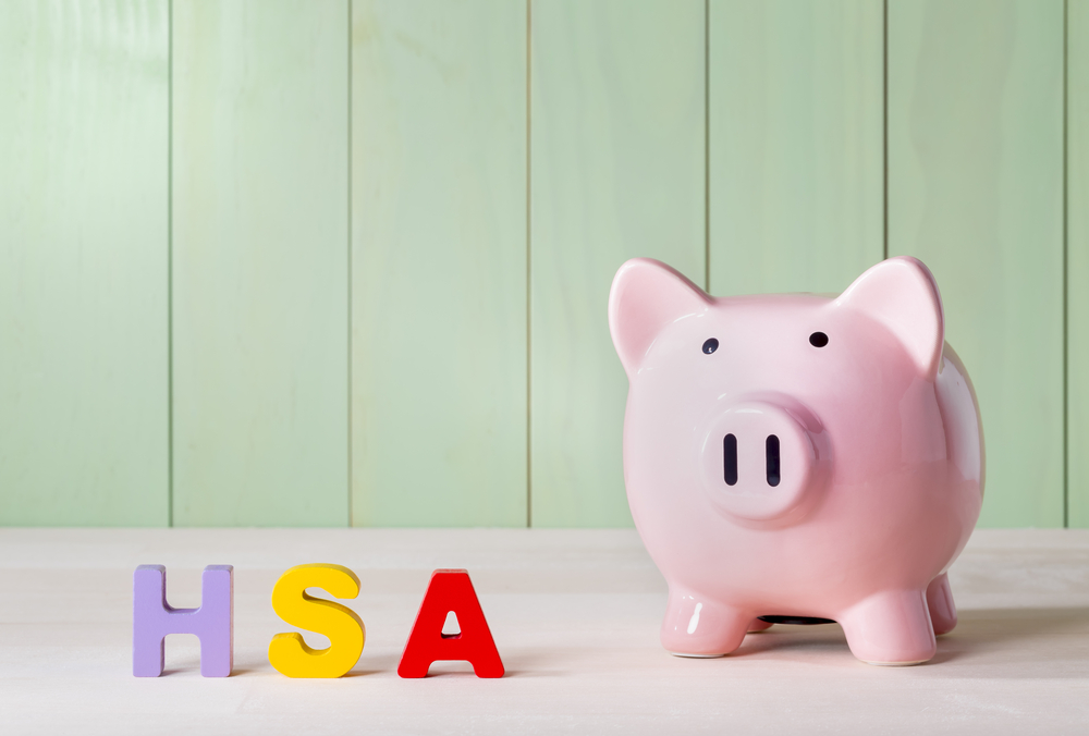 Piggy bank sitting next to letters spelling HSA